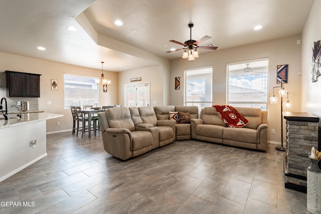 living room with recessed lighting, baseboards, and ceiling fan with notable chandelier