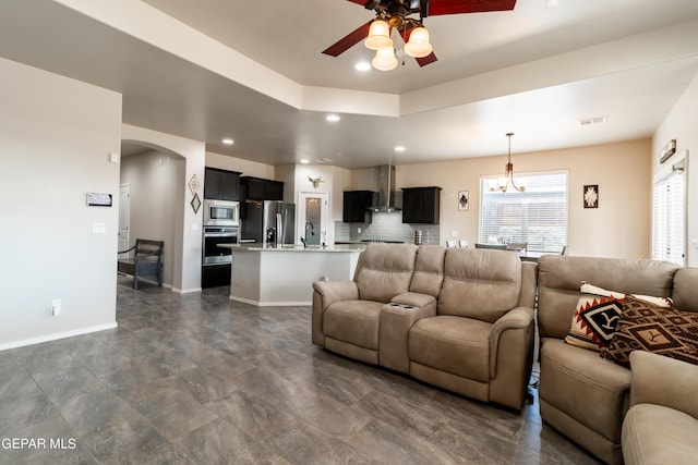 living area with arched walkways, recessed lighting, visible vents, baseboards, and ceiling fan with notable chandelier