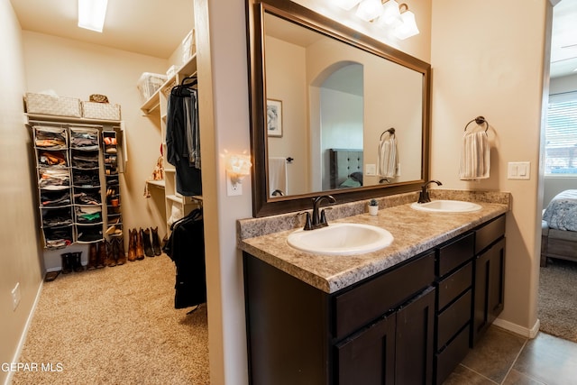 ensuite bathroom with a walk in closet, a sink, ensuite bath, and double vanity