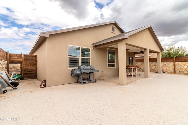 rear view of property with a patio, fence, and stucco siding