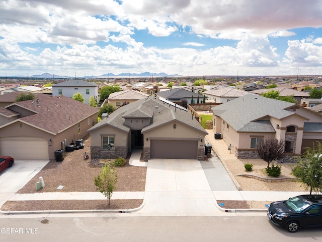 view of front of house featuring stone siding, concrete driveway, a residential view, and stucco siding