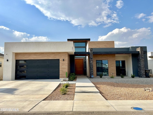 contemporary home with stucco siding, an attached garage, and concrete driveway