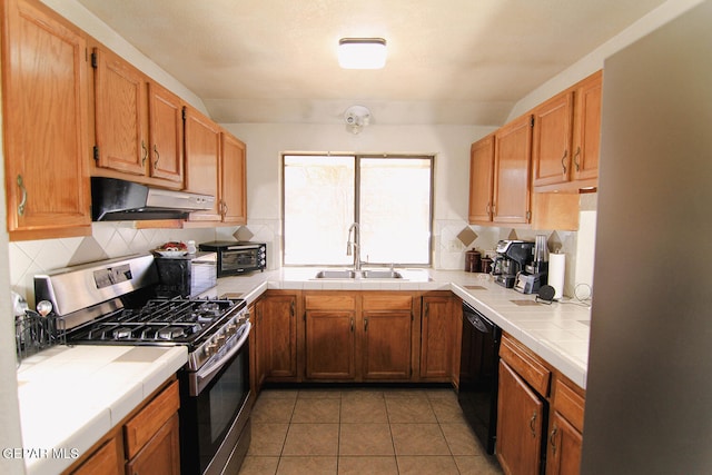 kitchen with decorative backsplash, gas range, sink, black dishwasher, and tile counters