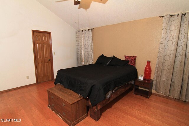 bedroom with a textured ceiling, vaulted ceiling, ceiling fan, and hardwood / wood-style flooring