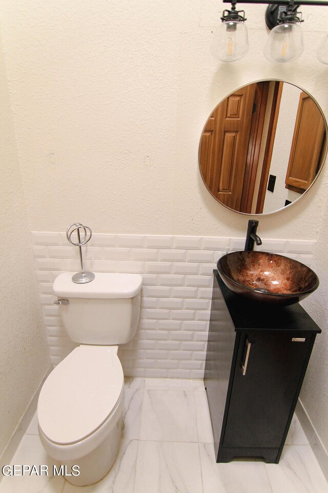 bathroom with tile walls, toilet, and vanity