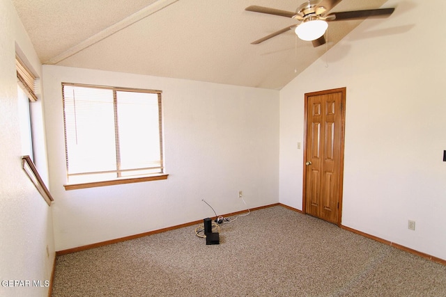 unfurnished room with carpet, a ceiling fan, vaulted ceiling, a textured ceiling, and baseboards