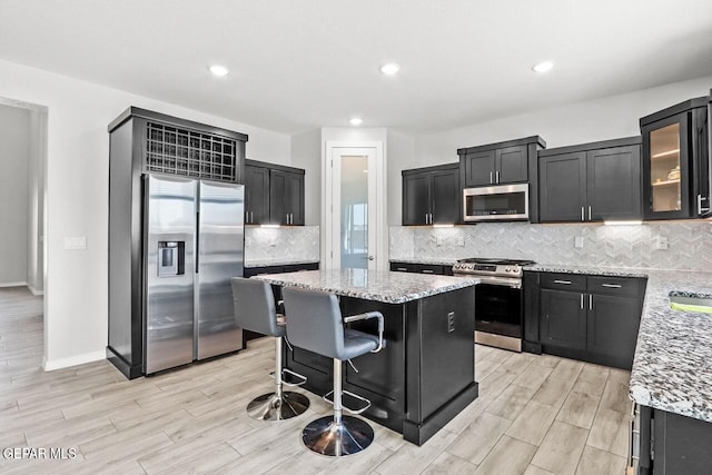 kitchen with a center island, light stone counters, appliances with stainless steel finishes, and decorative backsplash