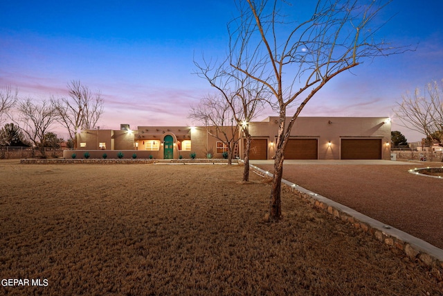 pueblo-style house featuring stucco siding, driveway, and a garage