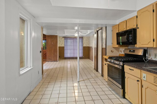 kitchen featuring stainless steel range with gas stovetop, light brown cabinetry, ceiling fan, and decorative backsplash