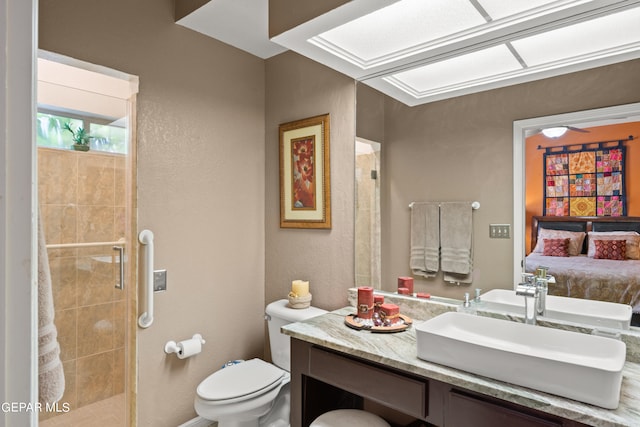 bathroom featuring a shower with shower door, toilet, vanity, and ceiling fan