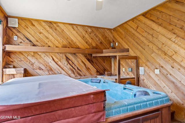 bedroom featuring a textured ceiling, ceiling fan, and wooden walls