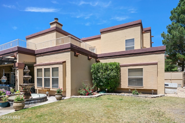 rear view of house with a yard and a balcony