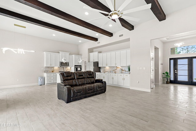 living room with beamed ceiling, light hardwood / wood-style flooring, and ceiling fan