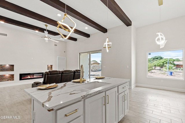 kitchen with ceiling fan, a wealth of natural light, pendant lighting, and an island with sink