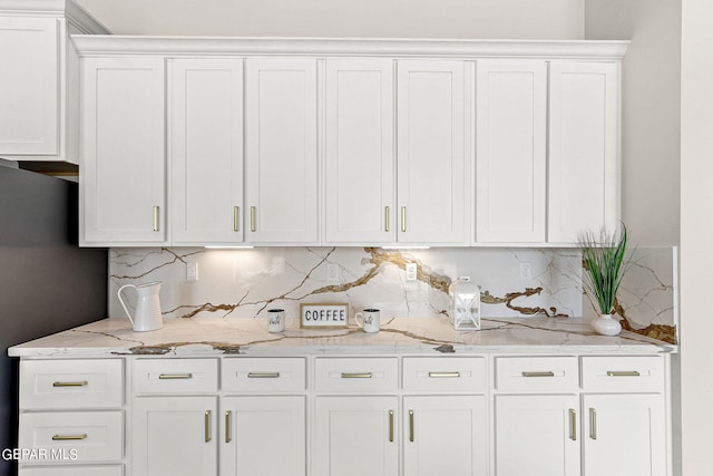 kitchen with light stone countertops, backsplash, and white cabinetry