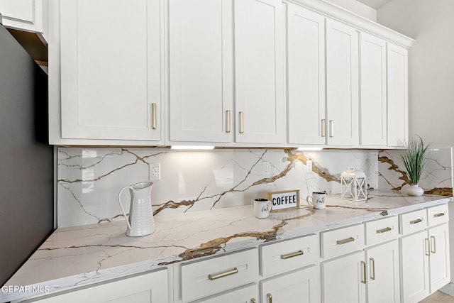 kitchen featuring light stone counters, decorative backsplash, and white cabinets