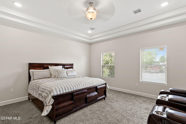 carpeted bedroom featuring ceiling fan and a tray ceiling