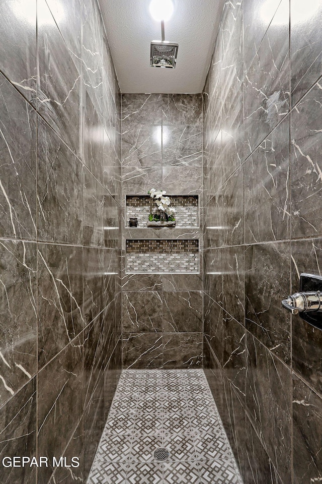 bathroom featuring a textured ceiling and tiled shower