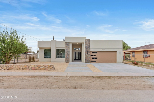 view of front facade with stucco siding, stone siding, fence, concrete driveway, and a garage