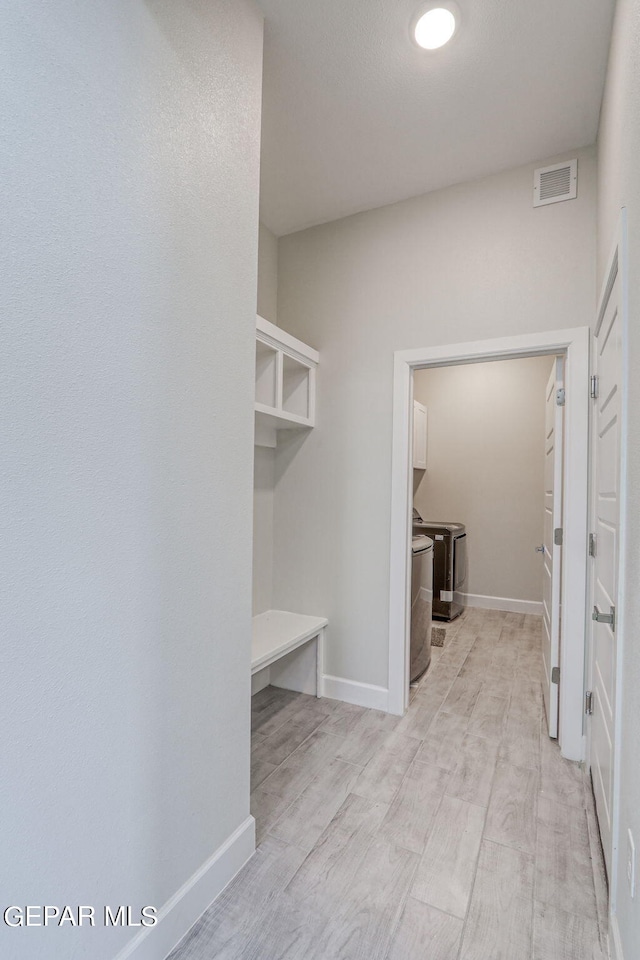 walk in closet featuring washing machine and dryer and light hardwood / wood-style floors