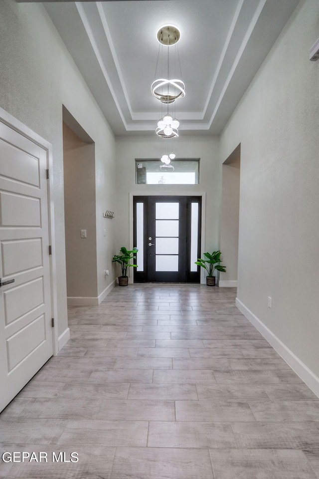 entrance foyer featuring a tray ceiling, a chandelier, and light hardwood / wood-style flooring