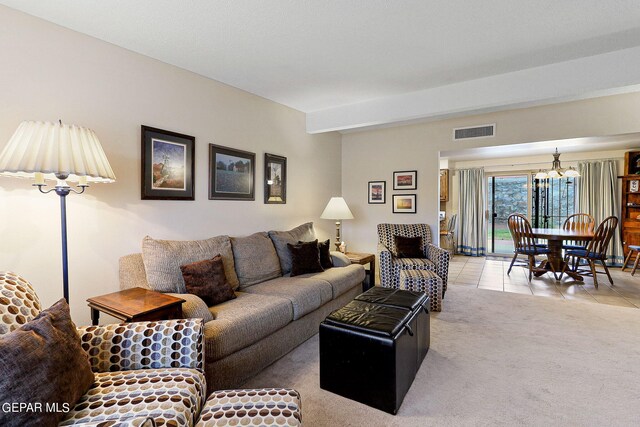 carpeted living room featuring an inviting chandelier