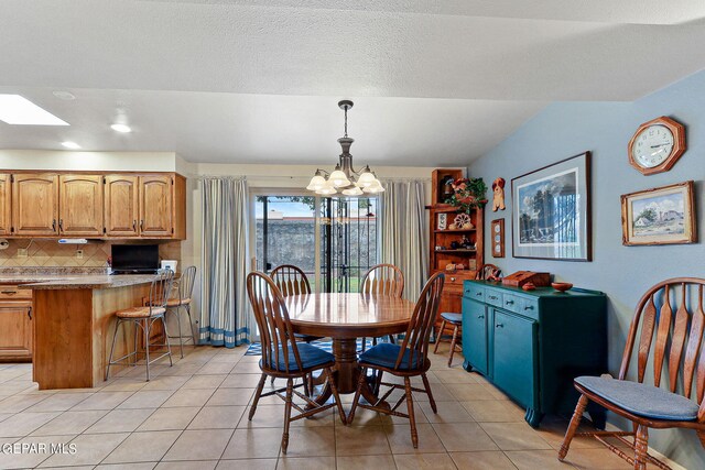 dining space featuring a textured ceiling, a skylight, an inviting chandelier, and light tile patterned flooring