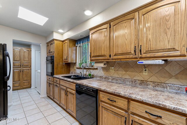 kitchen featuring black appliances, tasteful backsplash, a skylight, and sink