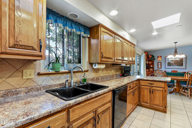 kitchen with black dishwasher, pendant lighting, kitchen peninsula, sink, and a skylight