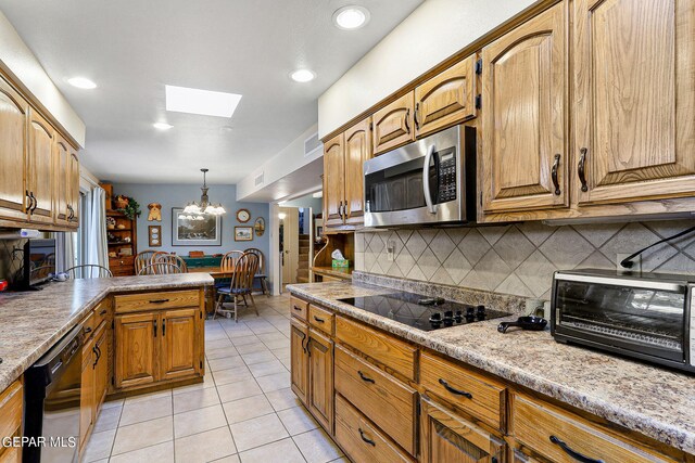 kitchen with pendant lighting, a notable chandelier, light tile patterned floors, black appliances, and decorative backsplash