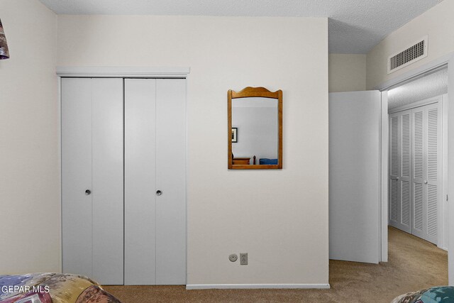 bedroom featuring a textured ceiling and light carpet