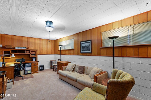 living room featuring ceiling fan, light colored carpet, and wooden walls