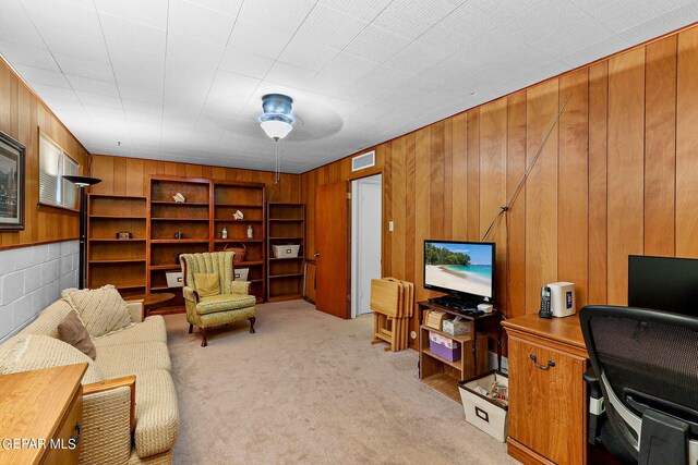 carpeted home office featuring wood walls