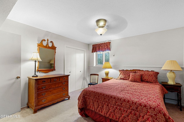 bedroom featuring a textured ceiling, light colored carpet, ceiling fan, and a closet