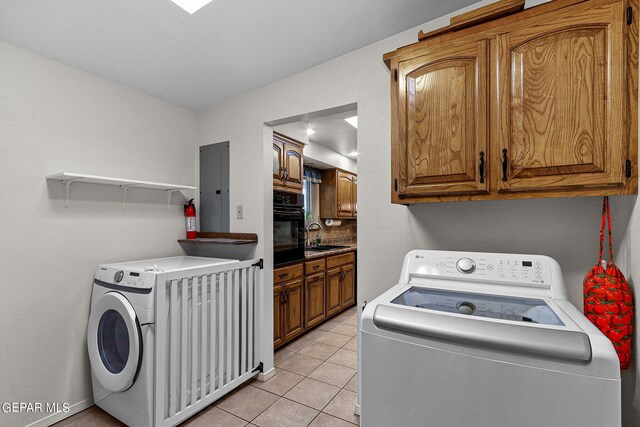 washroom with electric panel, washer and dryer, cabinets, and light tile patterned flooring