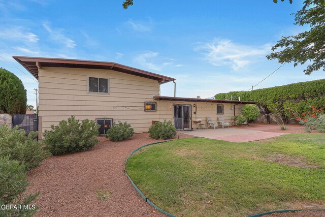 back of house with a lawn and a patio