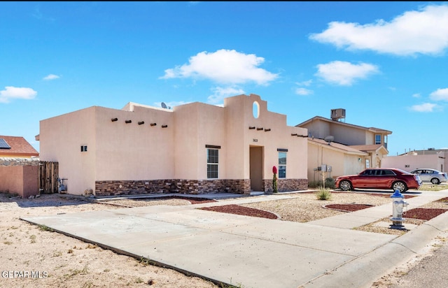 pueblo revival-style home with stone siding and stucco siding