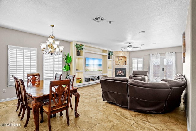 3000 Lookout Point Dr, El Paso, TX 79938 - dining room with a textured ceiling, visible vents, a tile fireplace, baseboards, and ceiling fan with notable chandelier