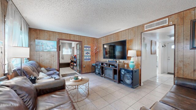 living room with wood walls, light tile patterned flooring, and a textured ceiling