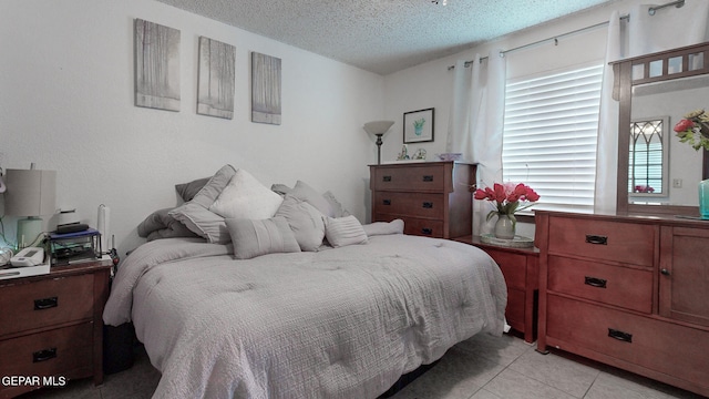 bedroom with a textured ceiling and light tile patterned floors