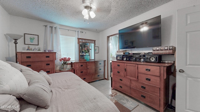 bedroom featuring a textured ceiling, ceiling fan, and light tile patterned floors