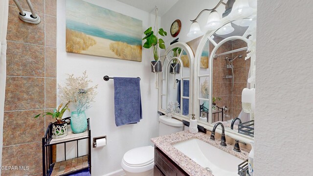 bathroom with tiled shower, toilet, and vanity