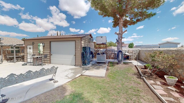 rear view of property with a yard, a garage, a patio, and an outdoor structure