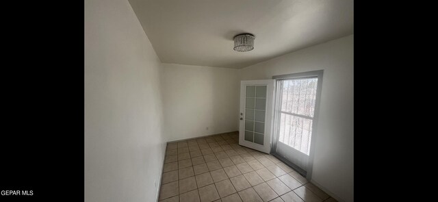 unfurnished room featuring lofted ceiling, light tile patterned flooring, and a healthy amount of sunlight