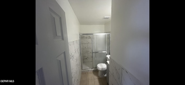 bathroom with toilet, an enclosed shower, and tile patterned floors