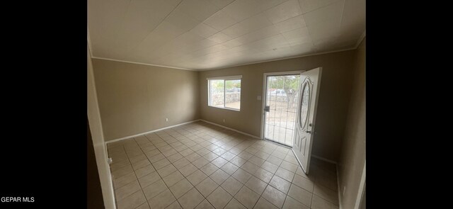 spare room with crown molding and light tile patterned floors