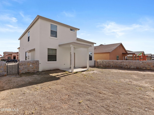 rear view of house featuring a patio area and stucco siding