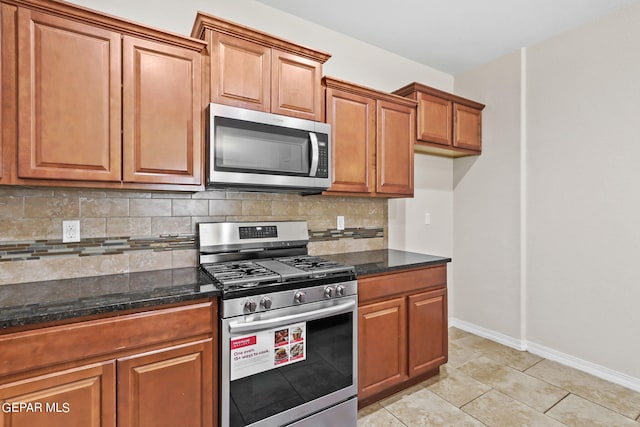 kitchen with dark stone countertops, light tile patterned floors, stainless steel appliances, and backsplash