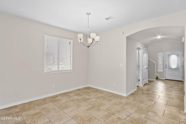 unfurnished room with a wealth of natural light, visible vents, arched walkways, and baseboards