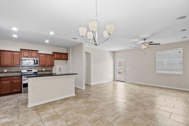 kitchen featuring dark countertops, open floor plan, stainless steel appliances, arched walkways, and decorative backsplash